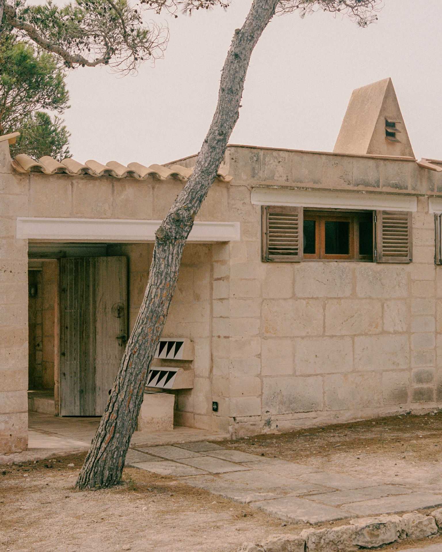Can Lis by Jørn Utzon, marés stone façade with a leaning pine tree