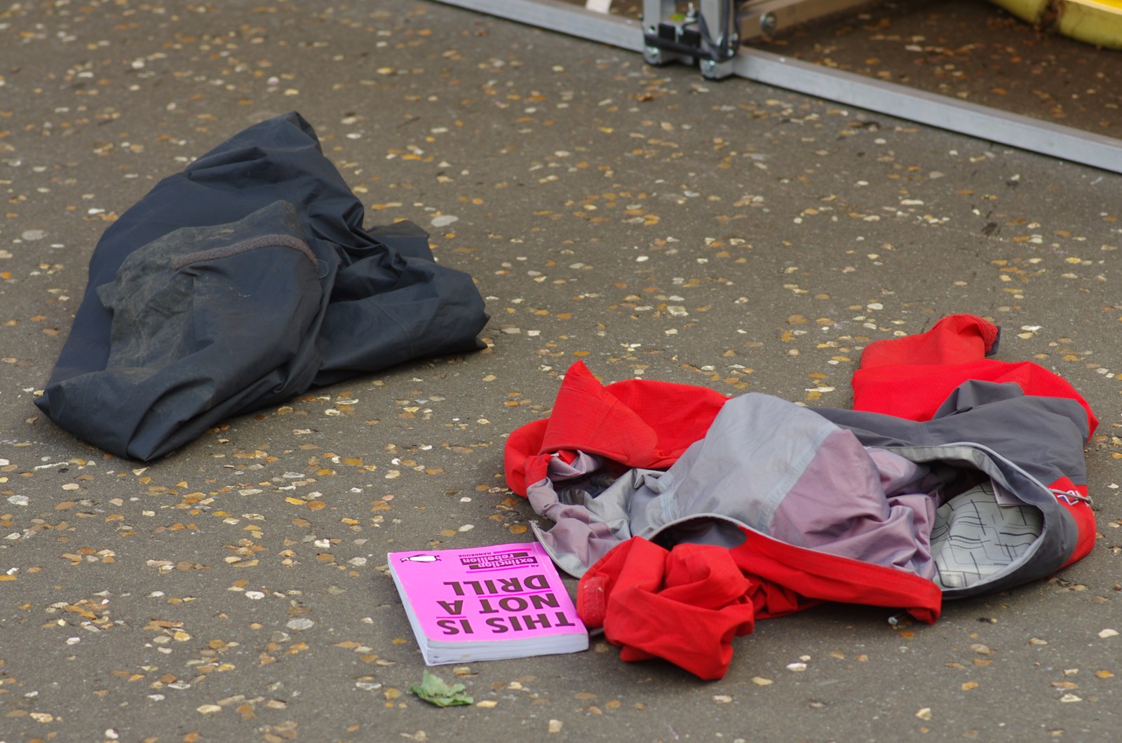 Discarded red and grey fabric beside a sign reading This Is Not A Drill during an Extinction Rebellion action at Tate Modern
